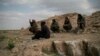 FILE - U.S.-backed Syrian Democratic Forces (SDF) fighters sit atop a hill in the desert outside the village of Baghuz, Syria, Feb. 14, 2019.