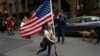 A girl parades up and down her block with a U.S. flag on her scooter, in the Greenwich Village neighborhood, during a partial easing of coronavirus restrictions in New York, May 14, 2020.
