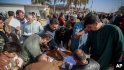 ARCHIVO - Seguidores del clérigo chií Muqtada al-Sadr firman una promesa de combatir la homosexualidad o la comunidad LGBTQ ante una mezquita en Kufa, Irak, el 2 de diciembre de 2022. 