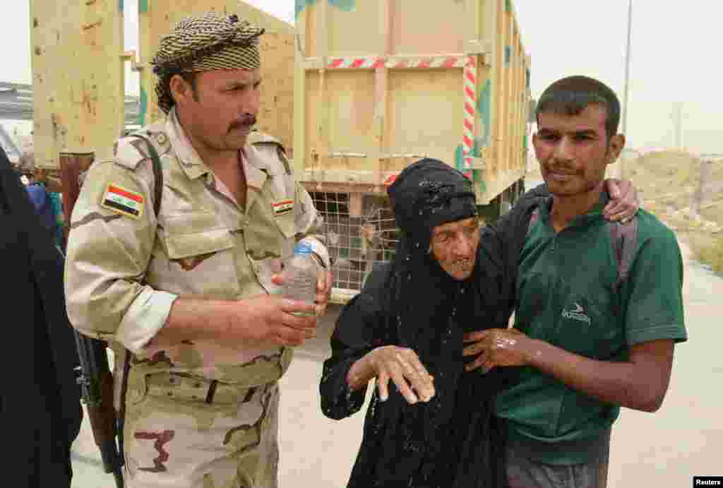 Seorang tentara Irak membantu warga sipil yang mengungsi dari pertempuran di kota Fallujah, Irak.