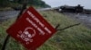 FILE - A destroyed military vehicle is seen near a landmine warning sign just outside the eastern Ukrainian town of Slaviansk, July 7, 2014. 
