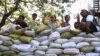 People flash the three-fingered symbol of resistance from behind a barricade of sacks blocking a road in Mandalay, Myanmar, March 5, 2021.