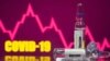 A test tube labelled with the Vaccine is seen in front of Covid-19 and stock graph logo in this illustration taken