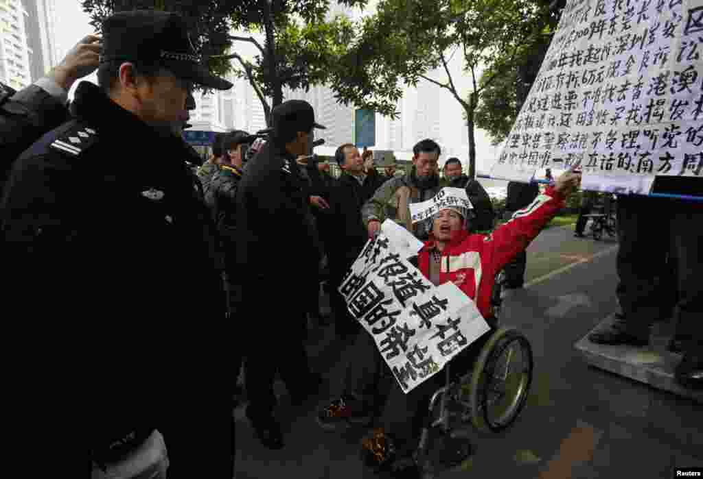 A supporter of the Southern Weekly newspaper in a wheelchair chants slogans in front of police officers near the newspaper&#39;s office in the southern Chinese city of Guangzhou, January 10, 2013.