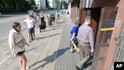 Personas en Varsovia, Polonia, observan las regulaciones contra el COVID-19 mientras votan en la elección presidencial, que fue aplazada en mayo por la pandemia. Junio 28 de 2019.