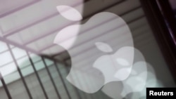 Los logotipos de la compañía Apple se reflejan en la ventana de vidrio afuera de una tienda Apple en Shanghai, China.