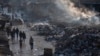 Palestinianos passam por uma pilha de lixo em chamas na Cidade de Gaza, 12 de fevereiro de 2025.