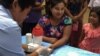 FILE - A public health worker takes a blood sample from a woman to be tested for malaria in Bo Rai district, Trat province, Thailand, Nov. 29, 2017.