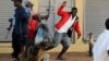 A Ugandan dodges the baton of a police officer in Kampala during an October, 2011 protest against high food prices and government corruption.