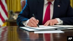 President Donald Trump signs an executive order to increase sanctions on Iran, in the Oval Office of the White House, June 24, 2019, in Washington. 