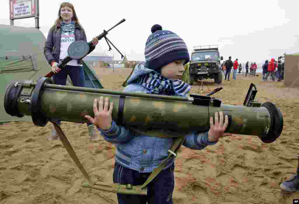 Seorang anak membawa rudal anti-tank Rusia dalam pameran senjata memperingati &#39;Hari Rusia&#39; di St.Petersburg.