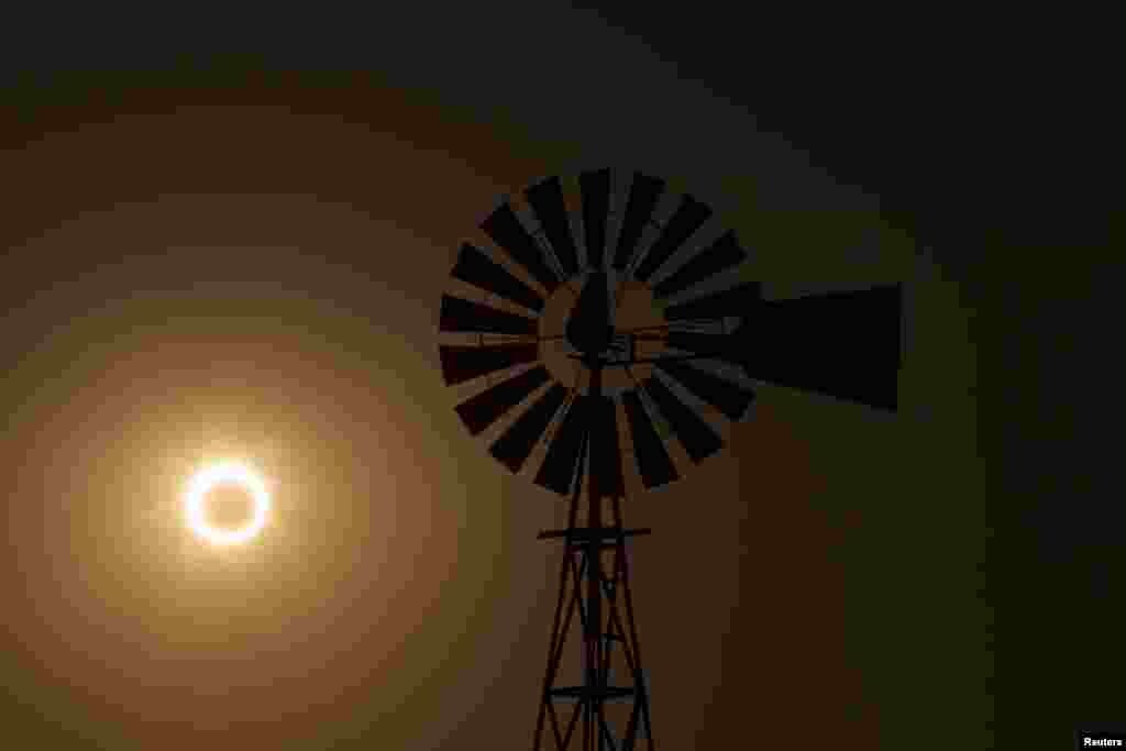 La Luna pasa entre el sol y la tierra detrás de un molino de viento en Albuquerque, Nuevo México.