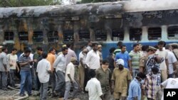 Trabajadores del ferrocarril y autoridades inspeccionan el vagón del tren que se incendió en la India, causando la muerte a al menos 47 personas.