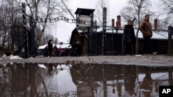 La gente camina junto a la puerta ''Arbeit Macht Frei" (El trabajo te libera) en el antiguo campo de concentración y exterminio alemán nazi Auschwitz-Birkenau en Oswiecim, Polonia, el jueves 26 de enero de 2023.