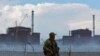 FILE - A serviceman with a Russian flag on his uniform stands guard near the Zaporizhzhia nuclear power plant outside the Russian-controlled city of Enerhodar in the Zaporizhzhia region, Ukraine, Aug. 4, 2022. 