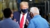 El presidente Donald Trump conversa con dos trabajadores en una planta de producción de la compañía Whirlpool en Clyde, Ohio, el jueves 6 de agosto de 2020.