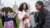 ARCHIVO - Las devotas de TikTok, Mona Swain, en el centro, y su hermana, Rachel Swain, a la derecha, ambas de Atlanta, posan con un cartel en el Capitolio en Washington, el 13 de marzo de 2024.