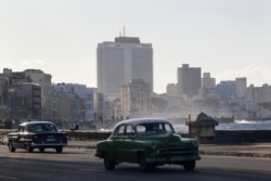 FILE - Vintage cars drive on the seafront boulevard El Malecon in Havana, Cuba, December 29, 2020.