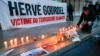FILE - A man places a candle near a banner as people pay tribute to Herve Gourdel, a French mountain guide who was beheaded by an Algerian Islamist group, in Lyon, France, Sept. 26, 2014.