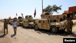 Vehículos militares iraquíes y combatientes chiitas se reunen en la represa Udhaim, al norte de Bagdad, el 1 de marzo, de 2015. 