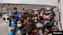 Migrantes de Centroamérica en busca de asilo, que fueron transportados en avión desde Brownsville a El Paso, Texas, y deportados de Estados Unidos, cruzan el puente fronterizo internacional Paso del Norte, Ciudad Juárez, México, el 22 de marzo de 2021.