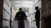 Un soldado vigila mientras un trabajador lleva cajas con materiales de votación para distribuir en todo el país antes de las elecciones generales del 28 de noviembre, en Tegucigalpa, Honduras, el 23 de noviembre de 2021.