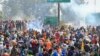 Para petani yang melakukan protes berdiri di balik asap yang diakibatkan gas air mata di dekat perbatasan Shambhu yang memisahkan negara bagian Punjab utara dan Haryana, hampir 200 km dari New Delhi, India, 14 Februari 2024. (Foto: AP)