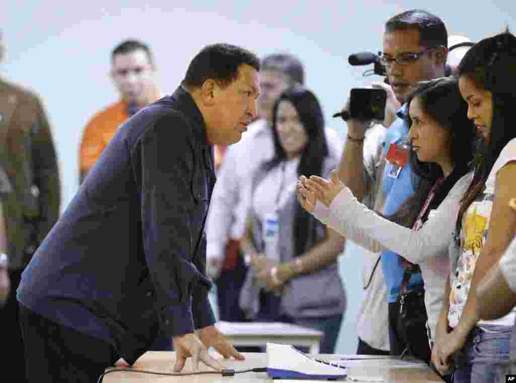Ch&aacute;vez, izquierda, habla con un empleado en las elecciones durante las votaciones presidenciales en Caracas, el 7 de octubre de 2012.