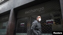 Un hombre usando una mascarilla pasa frente a un casa de cambio cerrada debido a la cuarentena, en el centro de Buenos Aires el 22 de mayo de 2020.