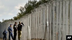 FILE - A police officer, second right, and border guard, right, of Poland patrol with Hungarian policemen along the temporary border fence on the Hungarian-Serbian border near Roszke, 180 kms southeast of Budapest, Hungary, Oct. 13, 2016.
