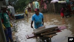 Warga membersihkan rumahnya yang terendam banjir di Itapetinga, negara bagian Bahia, Brazil, Selasa, 28 Desember 2021. (Foto: AP)