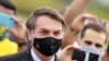El presidente de Brasil, Jair Bolsonaro, se encuentra en medio de partidarios que toman fotos con teléfonos celulares cuando sale de su residencia oficial.
