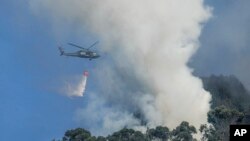 Un helicóptero rocía un incendio forestal en las montañas que dominan el este de Bogotá, Colombia, el lunes 22 de enero de 2024. 