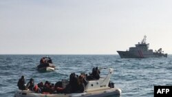 FILE - A handout image from France's Societe Nationale de Sauvetage en Mer on Feb. 18, 2019, shows British rescuers (front) helping some 20 migrants on a semirigid boat trying make their way from France across the English Channel.