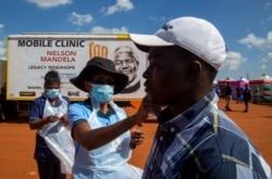 Un trabajador de la salud controla la temperatura de un hombre en cuarentena en una cancha de fútbol para detectar el COVID-19 en Lenasia South, sur de Johannesburg, Sudáfrica, el 21 de abril de 2020,