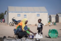 FILE - A displaced Burkinabe woman and child prepare food, in the Pissila town camp, near Kaya, Burkina Faso, Dec. 10, 2019.