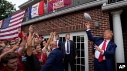 El expresidente Donald Trump lanza una pelota de fútbol americano a la multitud durante una visita a Alpha Gamma Rho, en la Universidad Estatal de Iowa antes de un partido de fútbol americano universitario el 9 de septiembre de 2023, en Ames, Iowa.