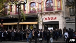 FILE - People stand in front of the Bataclan concert venue during ceremonies across Paris marking the second anniversary of the terror attacks of November 2015 in which 130 people were killed, in the French capital, Nov. 13, 2017. Rapper Medine's scheduled concerts at the Bataclan have caused controversy. 
