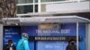 Personas con mascarillas esperan en una parada de autobús, donde se ve un cartel que muestra de la deuda nacional actual en medio de la pandemia de COVID-19 en Washington, el 31 de enero de 2022.