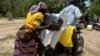 FILE - A Cameroonian displaced woman is seen loading her donated food onto a motorcycle outside a distribution center in Koza, in the extreme northern province, west of the Nigerian border, Sept. 14, 2016