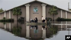Volunteers use a boat to recover sound equipment from a flooded church in the aftermath of Isaac, in Reserve, Louisiana, August 31, 2012.