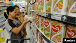 A sales assistant (back) helps a customer to select Dumex milk powder at a supermarket in Hefei, Anhui province, August 5, 2013.