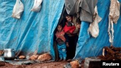 Displaced Syrian children look out from their tents at Kelbit refugee camp, near the Syrian-Turkish border, in Idlib province, Syria, Jan. 17, 2018. 