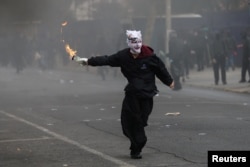 Un manifestante se prepara para lanzar un cóctel Molotov a la policía antidisturbios (no en la foto), durante enfrentamientos con la policía antidisturbios, en una manifestación del Primero de Mayo en Santiago, Chile, el 1 de mayo de 2024.