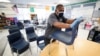 Des Moines Public Schools custodian Tracy Harris cleans chairs in a classroom at Brubaker Elementary School in Des Moines, Iowa, July 8, 2020.