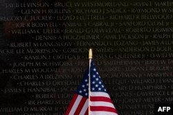 Una bandera estadounidense se encuentra contra un muro conmemorativo en el Memorial de la Guerra de Vietnam en el National Mall antes del Día de los Caídos en Washington, DC, el 26 de mayo de 2024.