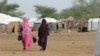 FILE - Malian women walk in Goudebou refugee camp in Burkina Faso, July 26, 2013.