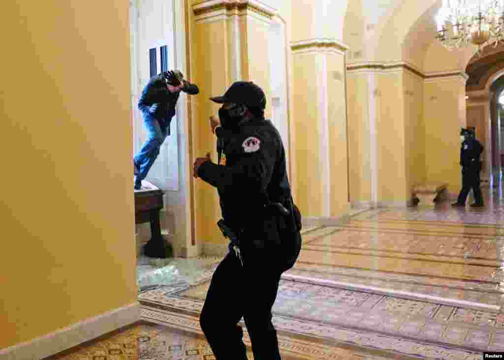 Un oficial de polic&#237;a del Capitolio de los Estados Unidos dispara gas pimienta a un manifestante que intenta ingresar al edificio del Capitolio. 