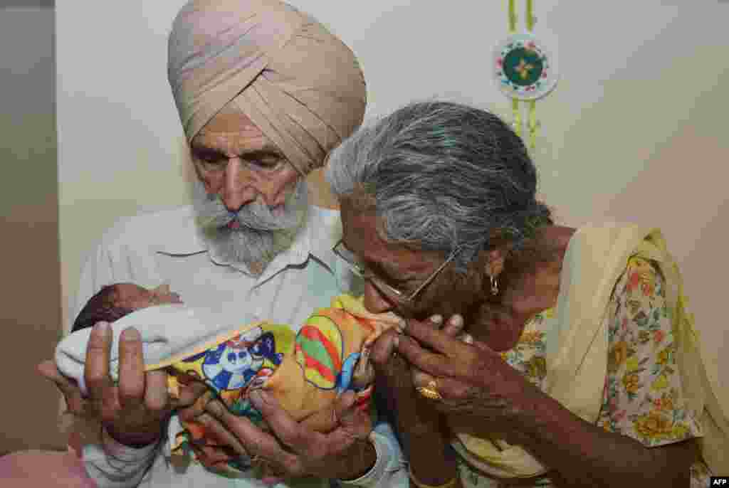 Pasangan suami istri Mohinder Singh Gill, 79 dan istrinya Daljinder Kaur, 70 menggendong bayi lelaki mereka, Arman, di rumahnya di Amritsar.&nbsp; Daljinder Kaur melahirkan anaknya dua bulan yang lalu setelah menjalani perawatan IVF bersama suaminya di klinik kesuburan di negara bagian India utara, Haryana.