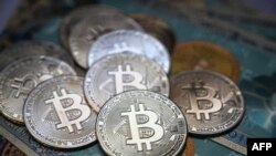 La fotografía ilustrativa tomada el 19 de julio de 2021 en Estambul muestra un billete físico y las imitaciones de la moneda criptográfica Bitcoin.